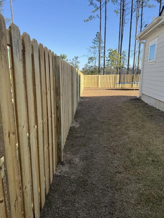 Board on board wood privacy fence with dog-ear tops along a side yard