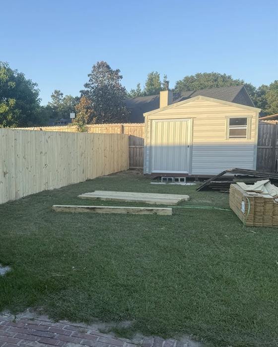 New wood stockade privacy fence around a backyard with a shed